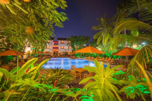 a pool with tables and umbrellas and a hotel at Villa Blanca Huatulco in Santa Cruz Huatulco