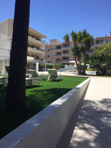 a park with chairs and a tree and a building at Flacalco Hotel & Apartments in Cala Ratjada