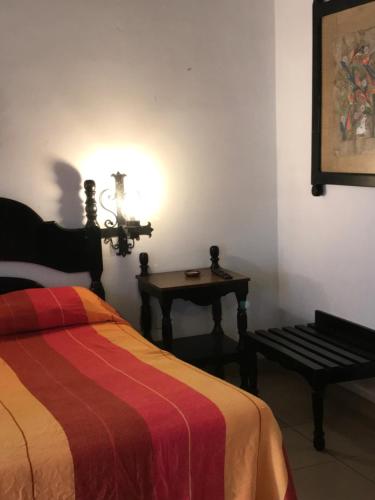 a bedroom with a bed and a table with a lamp at Hotel Villa de Flores in Uruapan del Progreso
