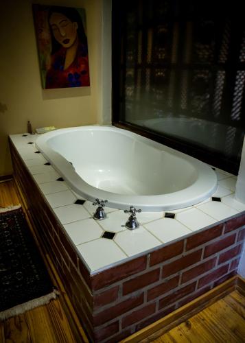 a large bath tub in a bathroom with a brick wall at Mon-Ae Guesthouse in Klerksdorp