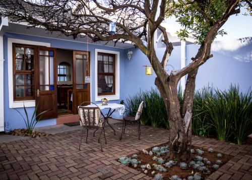 a table and chairs next to a tree in front of a house at Mon-Ae Guesthouse in Klerksdorp