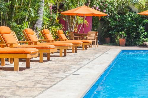 a pool with chairs and umbrellas next to a pool at Villa Blanca Huatulco in Santa Cruz Huatulco