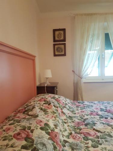 a bedroom with a bed with a floral bedspread and a window at Accasamia Terricciola in Terricciola