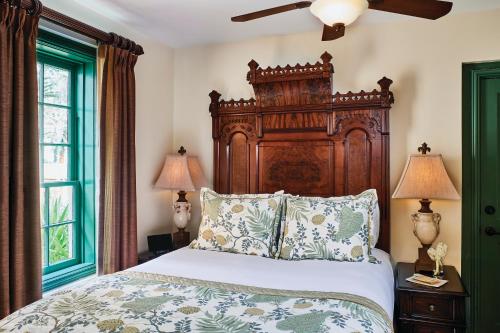 a bedroom with a large bed with a wooden headboard at The Collector Inn (Adults Only) - Saint Augustine in Saint Augustine