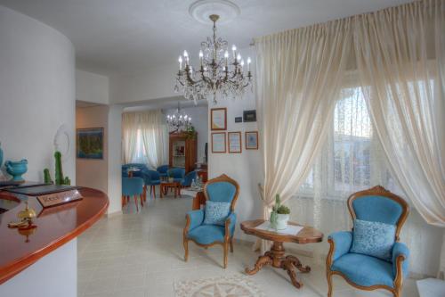 un soggiorno con sedie, tavolo e lampadario pendente di Hotel Noris a Finale Ligure