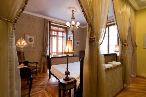 a bedroom with a bed and a table and two windows at Posada Real Los Cinco Linajes in Arévalo