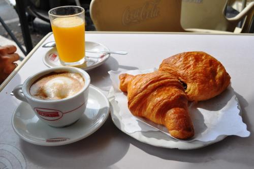 a plate of croissants and a cup of coffee and orange juice at Hotel Clodia in Chioggia