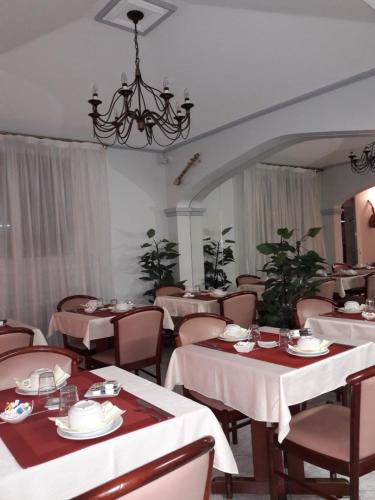 un restaurant avec des tables et des chaises blanches et un lustre dans l'établissement Hotel les Troenes, à Montpellier