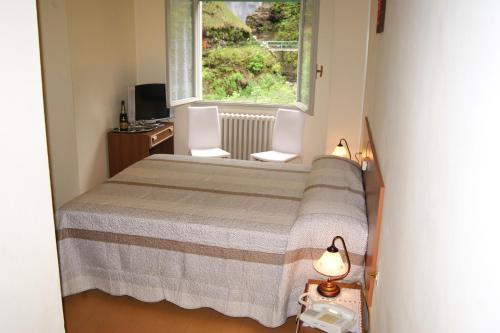 a bedroom with a bed with two chairs and a window at Albergo Ristorante Pace in Bognanco