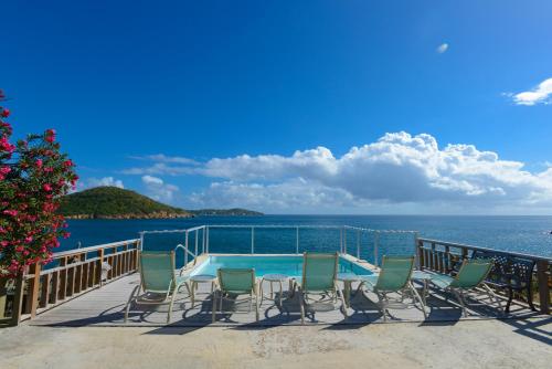 eine Terrasse mit Stühlen, einen Pool und das Meer in der Unterkunft Lindbergh Bay Hotel in Lindbergh Bay