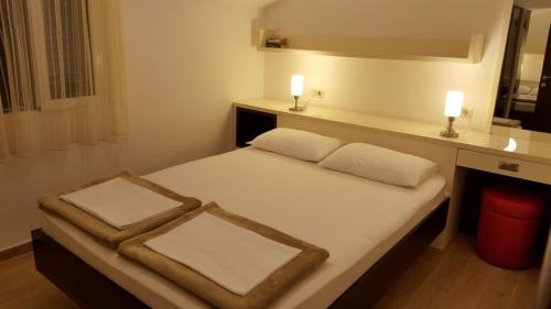 a bedroom with a bed with two white pillows at Apartments TMV Dragovic in Sveti Stefan