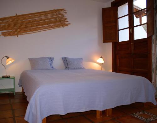 a bedroom with a white bed with two lamps and a window at Casa Creativa in Hermigua