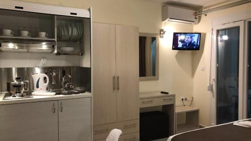 スカラ・マリオンにあるLydia Studiosの白いキャビネットと壁掛けテレビ付きのキッチン