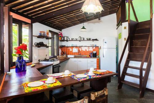 a kitchen with a wooden table and a refrigerator at Localização Incrível - Praia e Vila in Praia do Forte