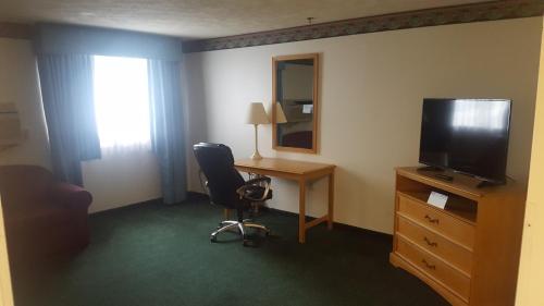 a hotel room with a desk and a television and a chair at Baymont by Wyndham Coeur D Alene in Coeur d'Alene