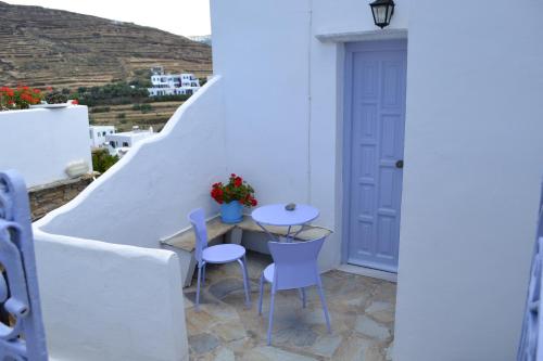 a small table and chairs on a balcony with white walls at Studio Ioanna Tinos in Kionia