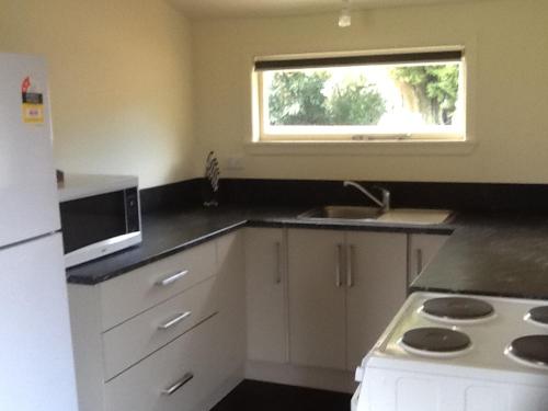 a kitchen with a white refrigerator and a window at River Terrace Cottage in Motueka