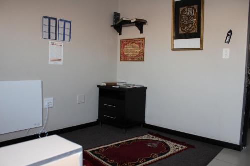 a room with a black dresser and a white wall at Alcazaba Hotel in Johannesburg