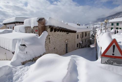a building covered in snow with a sign at Il Lavatoio Dimora Storica in Castel di Sangro