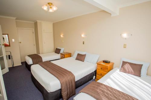a hotel room with three beds in a room at Parklands Motor Lodge Timaru in Timaru