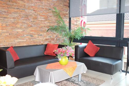 a living room with two black couches and a table at Alcazaba Hotel in Johannesburg
