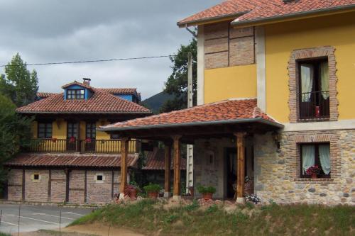 a large yellow house with a balcony on a street at Conjunto Hotelero La Pasera in Soto de Cangas