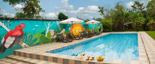 a pool with a mural next to chairs and umbrellas at Casa de Piedra in Mindo