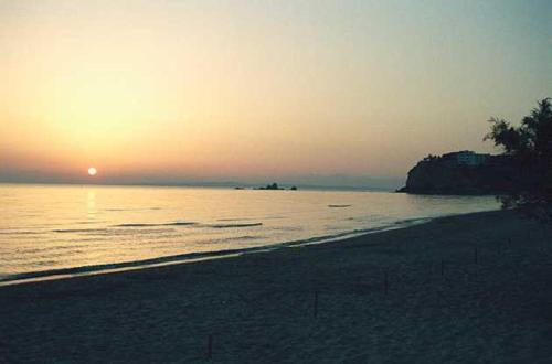 a beach with the sun setting in the ocean at Anetis Hotel in Tsilivi