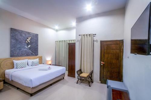 um quarto com uma cama e uma cadeira em JM Hotel Kuta Lombok em Kuta