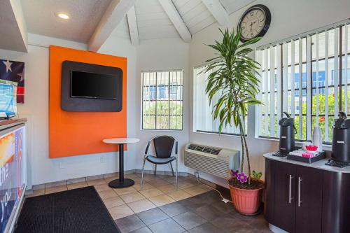 a living room with a clock on the wall and a plant at Motel 6-Yuma, AZ - East in Yuma