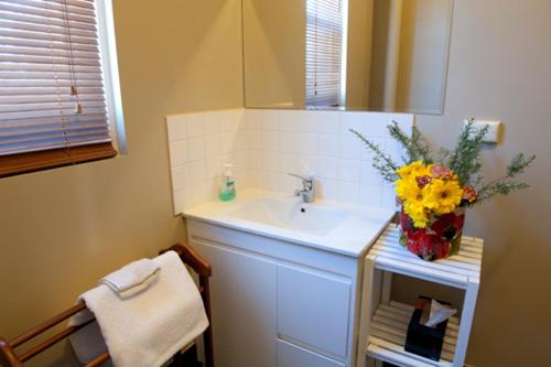 a bathroom with a sink and a vase of flowers at Webster Apartment in Ballarat