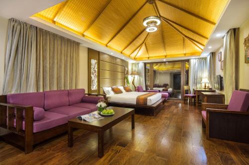 a hotel room with a bed and a purple couch at Sanya Yalong Bay Villas & Spa in Sanya