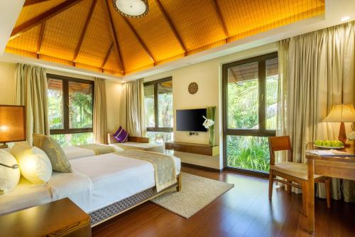 a bedroom with a bed and a desk and windows at Sanya Yalong Bay Villas & Spa in Sanya