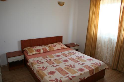 a bedroom with a bed with a floral bedspread at Apartments Sara in Vlašići