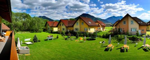 a group of houses on a green field with mountains at AHA Jasná Apartmány in Liptovský Mikuláš