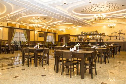 a restaurant with tables and chairs in a room at Salut Hotel Almaty in Almaty