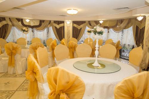 a room with a table with yellow chairs and a table with a white table cloth at Salut Hotel Almaty in Almaty