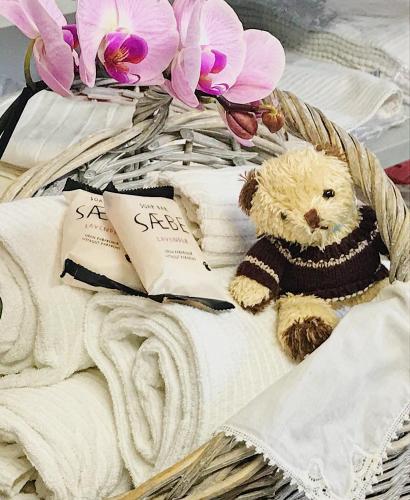 a teddy bear sitting on a basket with towels at Le Tartarughe rooms in Magliano in Toscana