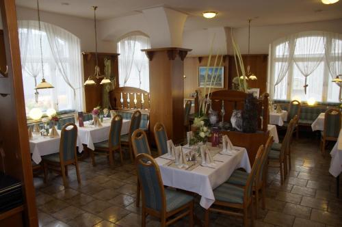 un restaurante con mesas y sillas blancas y ventanas en Ratskeller Thum en Thum