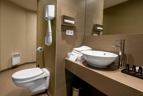 a bathroom with a toilet and a sink and a phone at Hotel Acacia in Bruges
