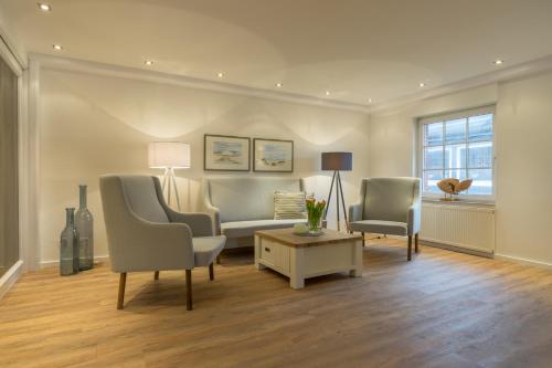 a living room with two chairs and a couch and a table at Strandfliederhaus in Norderney