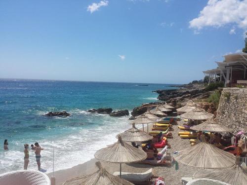 a beach with many umbrellas and people on the beach at Guesthouse Riviera "XH&M" Dhermi in Dhërmi