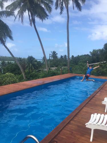 a man jumping into a swimming pool with palm trees at Muri Vista Villas in Rarotonga