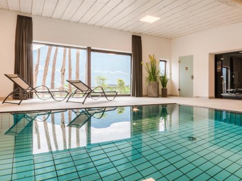 a swimming pool with two chairs in a room at Garni Hotel Katzenthalerhof in Lana