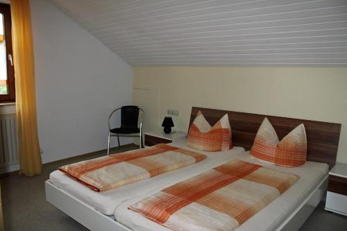 sypialnia z 2 łóżkami z pomarańczowymi poduszkami i krzesłem w obiekcie Ferienwohnung Ausblick w mieście Weißensberg