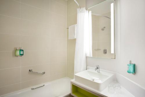 een witte badkamer met een wastafel en een bad bij Leonardo Hotel Manchester Central in Manchester