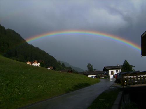 a rainbow in the sky over a road at Gastehaus Alpenruh in Prägraten am Großvenediger
