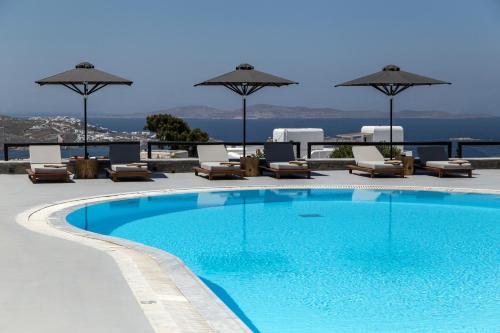 a swimming pool with chairs and umbrellas on a building at My Mykonos Hotel in Mikonos