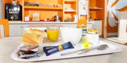 a tray with a plate of food and a glass of orange juice at Première Classe Martigues in Martigues