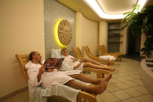 un hombre y una mujer sentados en las camas en un spa en Hotel Bellavista, en Canazei